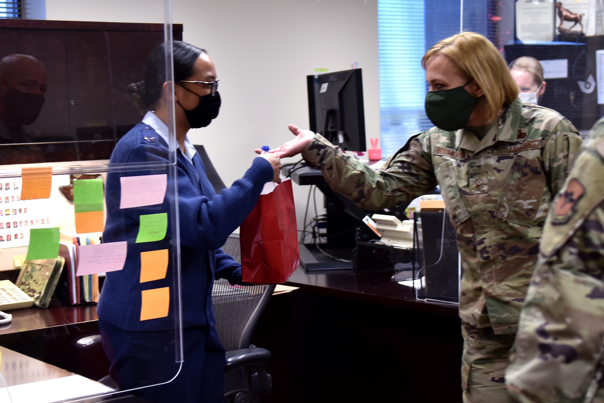 U.S. Air Force Chief Master Sgt. Casy Boomershine, 17th Training Wing command chief, gives a Goodfellow member a goody bag in the Norma Brown Building on Goodfellow Air Force Base, Texas, Nov. 17, 2020. Col. Andres Nazario, 17th Training Wing commander and Boomershine handed bags out to several offices in multiple squadrons. (U.S. Air Force Photo by Staff Sgt. Seraiah Wolf)
