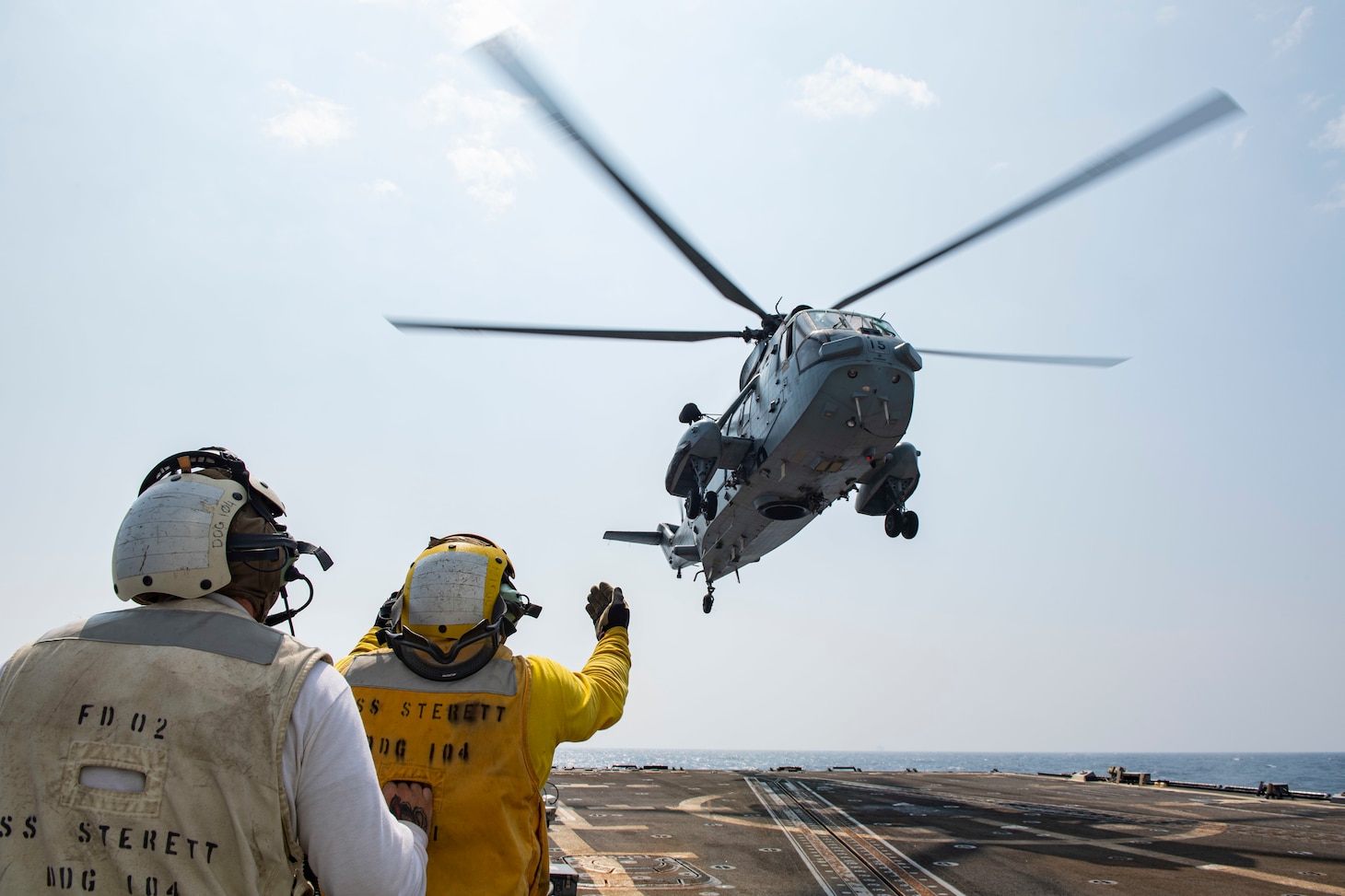 Damage Controlman 1st Class Ryan Sandoval, from Redlands, Calif., monitors Boatswain's Mate 2nd Class Kelvin Tyler, from Philadelphia, as he directs an Indian Navy Sea King Mk42B helicopter during a Malabar 2020 cross deck landing exercise on the flight deck of the guided-missile destroyer USS Sterett (DDG 104).