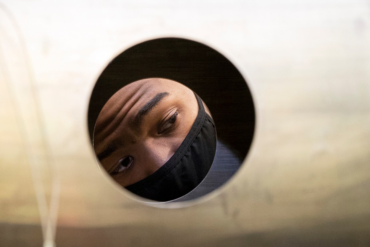 A sailor's face is visible through a circular opening on a section of a mine.