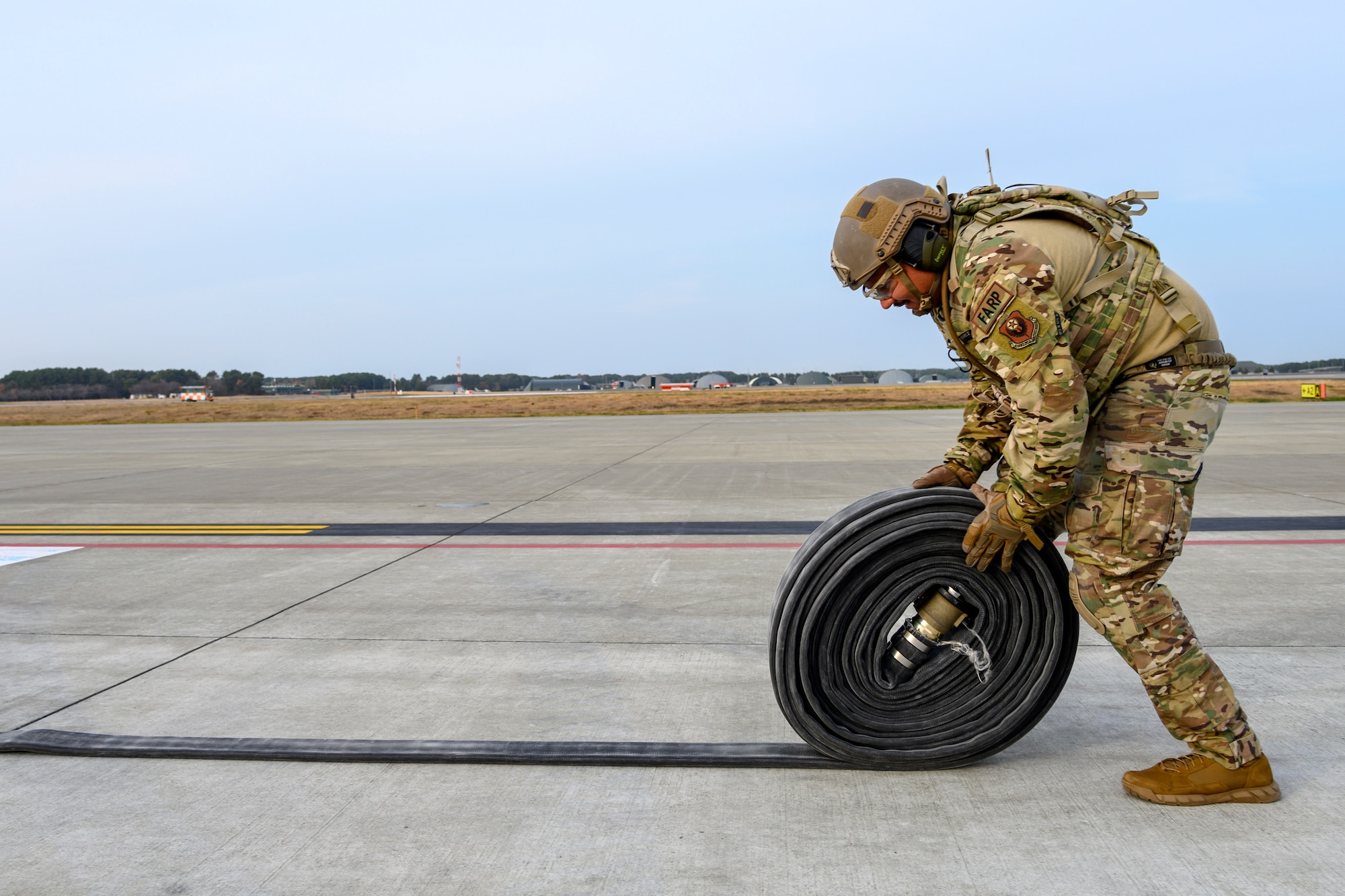 A U.S. Airman with the 1st Special Operations Squadron from Kadena Air Base, Japan, rolls up a fuel hose during a forward area refueling point (FARP) training at Misawa Air Base, Japan, Nov. 18, 2020. FARP ensures the rapid transfer of fuel from one aircraft to another. In this case, an MC-130J and two F-16 Fighting Falcons. (U.S. Air Force photo by Airman 1st Class China M. Shock)
