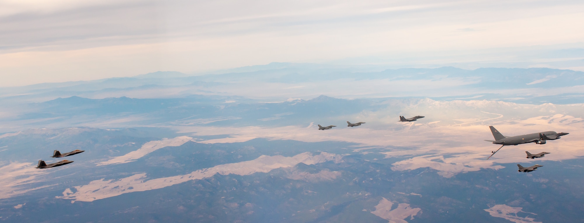 F-22s, F-15Es and F-16s fly alongside a KC-46