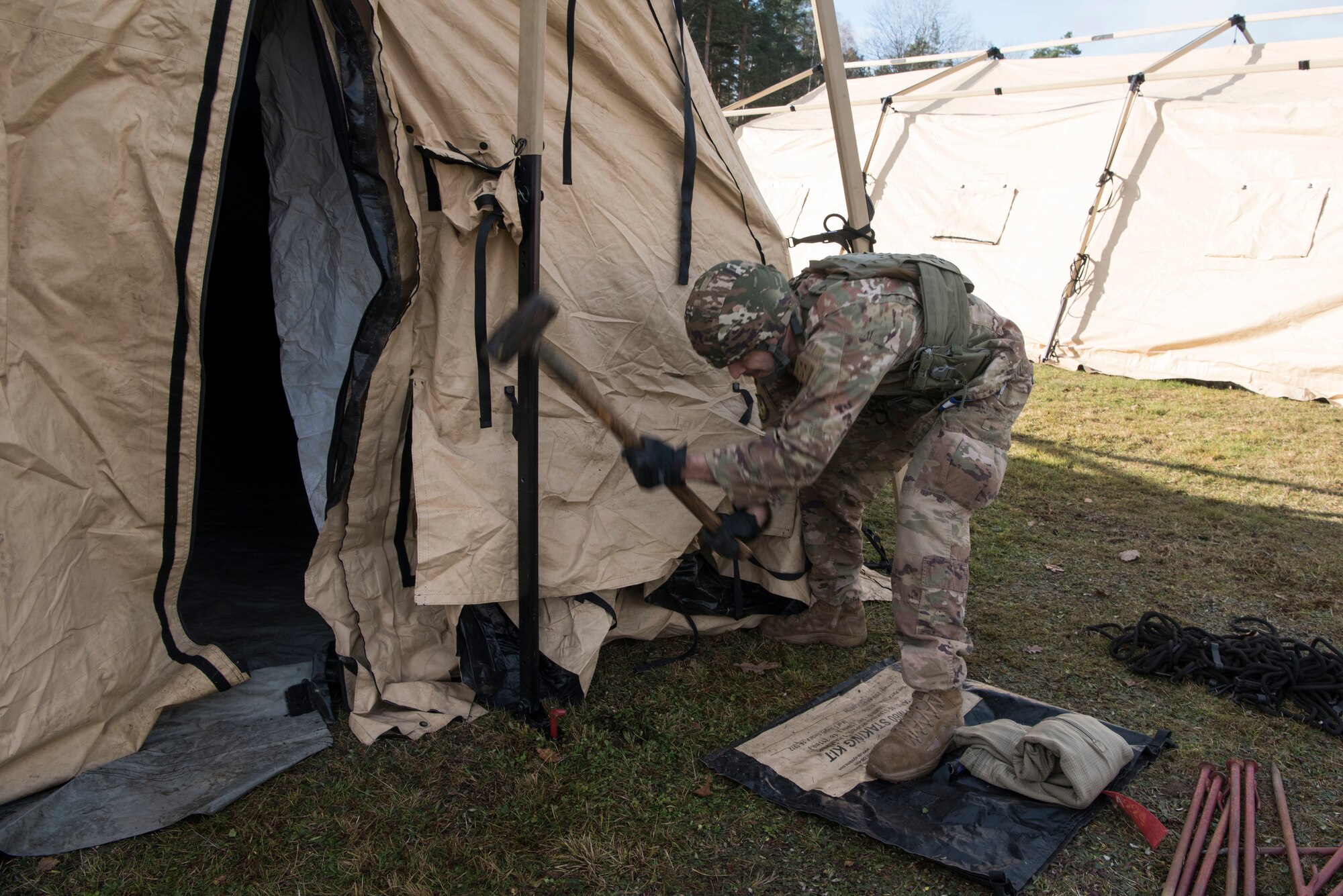 U.S. Air Force Staff Sgt. Anthony Palmer, 435th Construction and Training Squadron heavy equipment and pavements operator, drives a stake into the ground to secure an expeditionary tent during exercise Agile Wolf 21-01