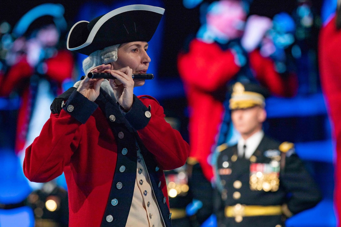 A soldier dressed a white wig and uniform similar to Revolutionary War-era clothing plays the flute.
