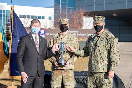 Navy Rear Adm. William W. "Trey" Wheeler III, U.S. Strategic Command chief of staff, right, and Vice Adm. (Ret.) Walter "Ted" Carter, the president of the University of Nebraska, present the Omaha Trophy to Col. Michael Hatfield, commander of the 100th Missile Defense Brigade, during a ceremony at U.S. Army Space and Missile Defense Command headquarters at Peterson Air Force Base, Colo., Nov. 19, 2020. This is the first time an Army unit and the first time an Army National Guard unit has been selected for this prestigious honor, which recognizes outstanding support to the USSTRATCOM mission of strategic deterrence.