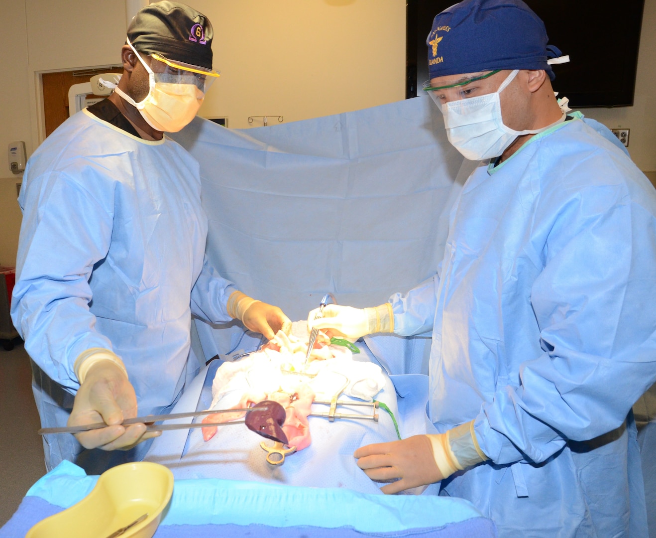 Petty Officer 1st Class Wesley Middleton, left, removes a simulated liver during a mock laparotomy assisted by Petty Officer 2nd Class Domenick Llanda. Both are instructors in the Medical Education and Training Campus Surgical Technologist program.  Army, Navy and Air Force ST students are becoming familiar with laparoscopic and laparotomy procedures, which are more universally practiced in the surgical field, after a curriculum update to move the training forward.