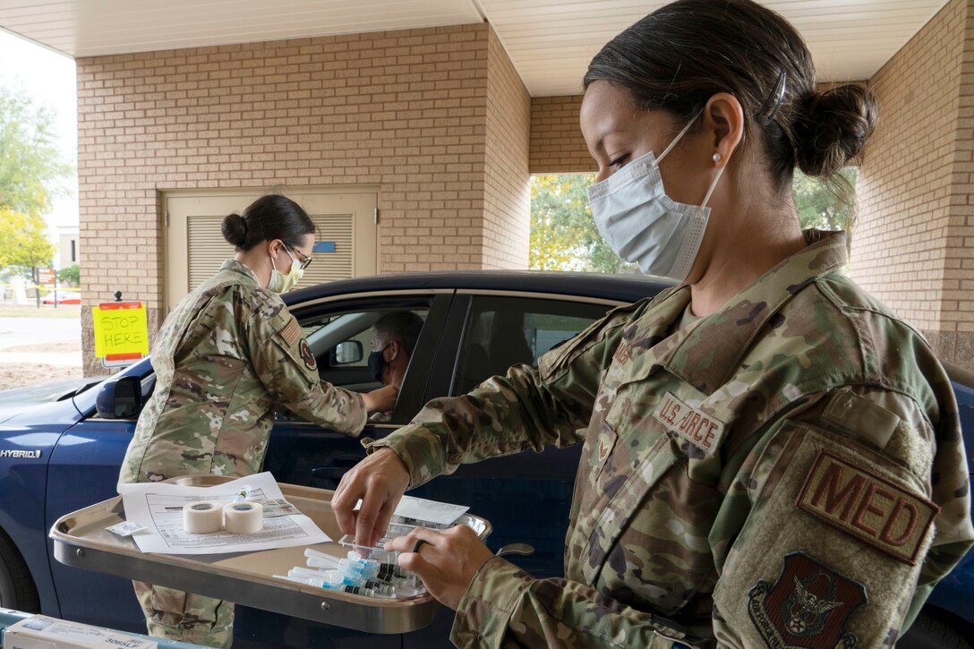 An airmen sorts through medical supplies while another helps a motorist.