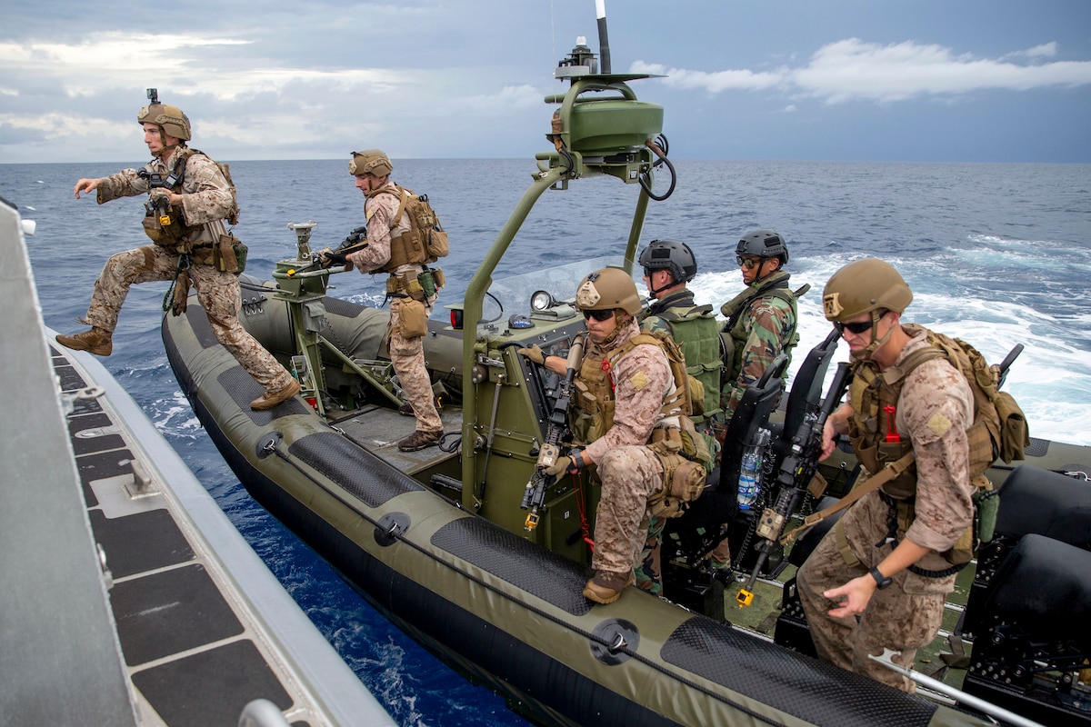 A Marine steps onto a ship from a small boat, as other U.S. and Dutch Marines prepare to do the same.