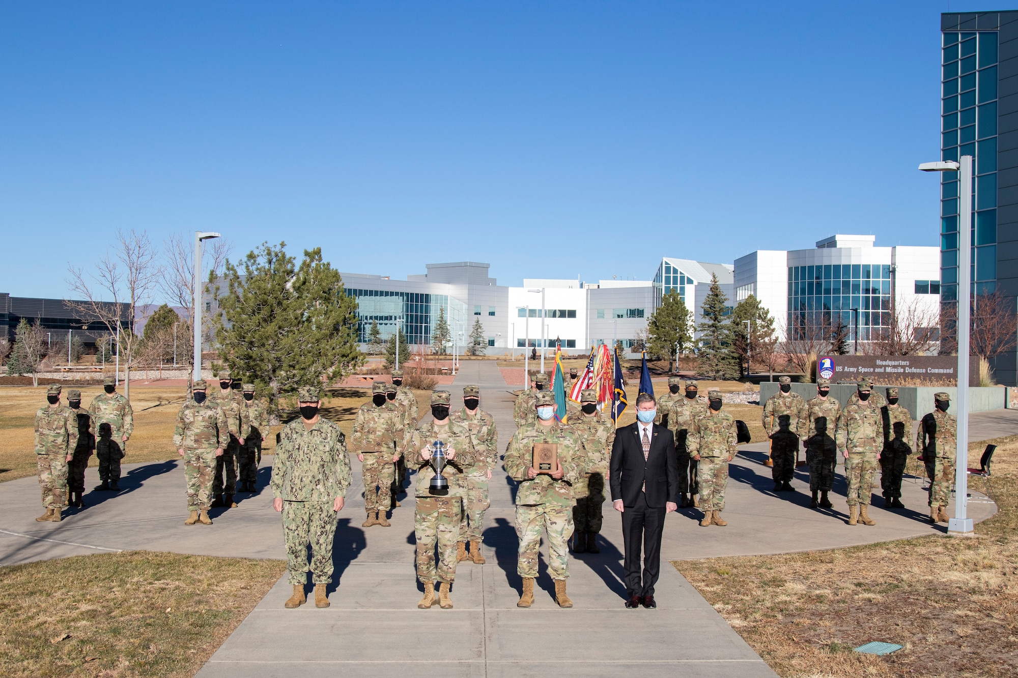 A formation of 100th Missile Defense Brigade Soldiers stand behind Navy Rear Adm. William W. "Trey" Wheeler III, U.S. Strategic Command chief of staff, left, Col. Michael Hatfield, commander, 100th Missile Defense Brigade, Sgt. Maj. Jeremy Christensen, operations sergeant major for the 100th, and Vice Adm. (Ret.) Walter "Ted" Carter, the President of the University of Nebraska,
