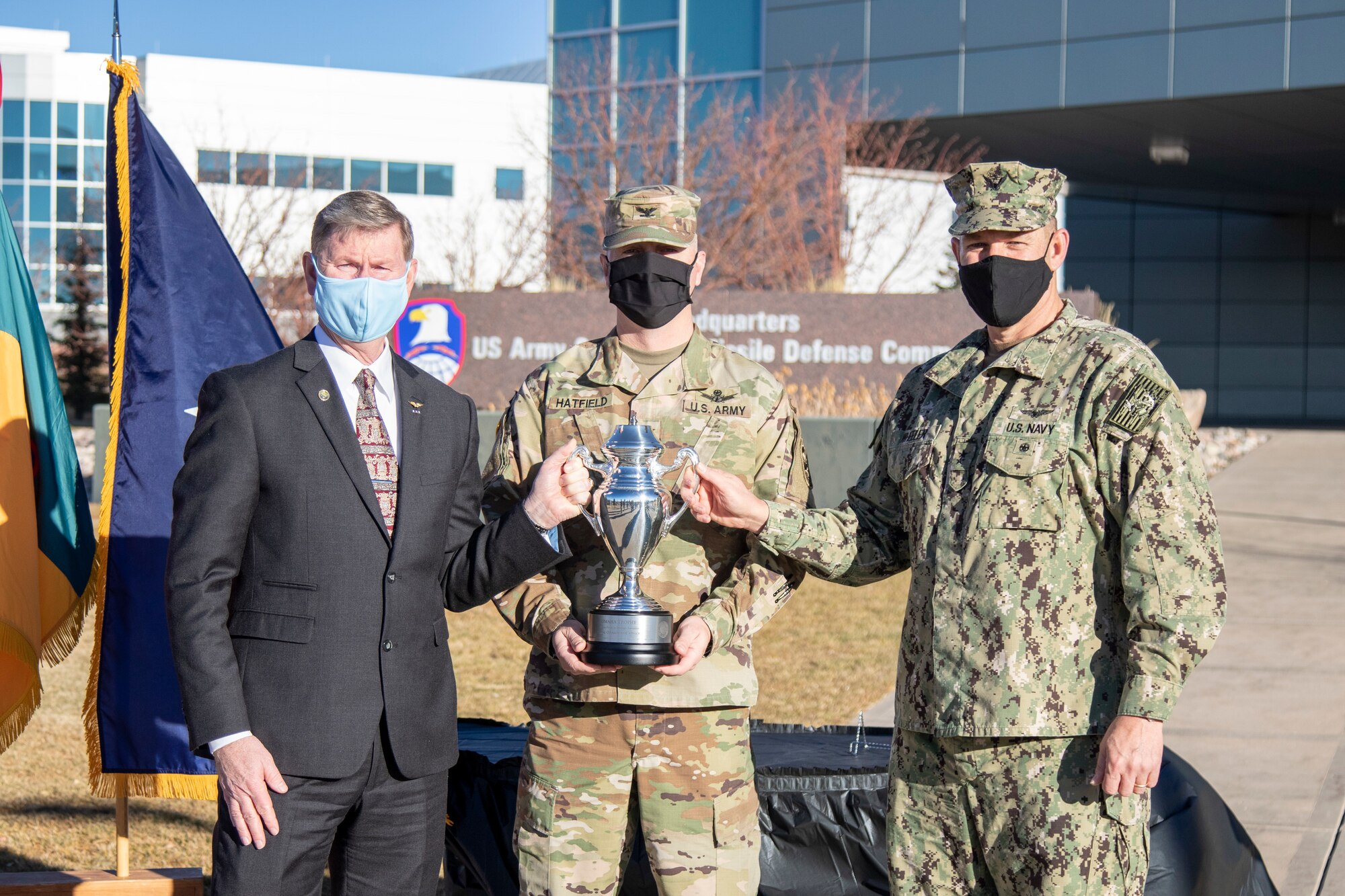 Navy Rear Adm. William W. "Trey" Wheeler III, U.S. Strategic Command chief of staff, right, and Vice Adm. (Ret.) Walter "Ted" Carter, the President of the University of Nebraska, present the Omaha Trophy to Col. Michael Hatfield, commander of the 100th Missile Defense Brigade,