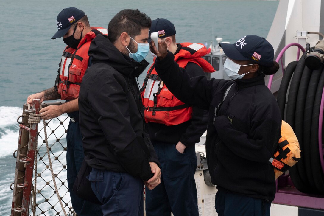 A sailor checks the temperature of a man.