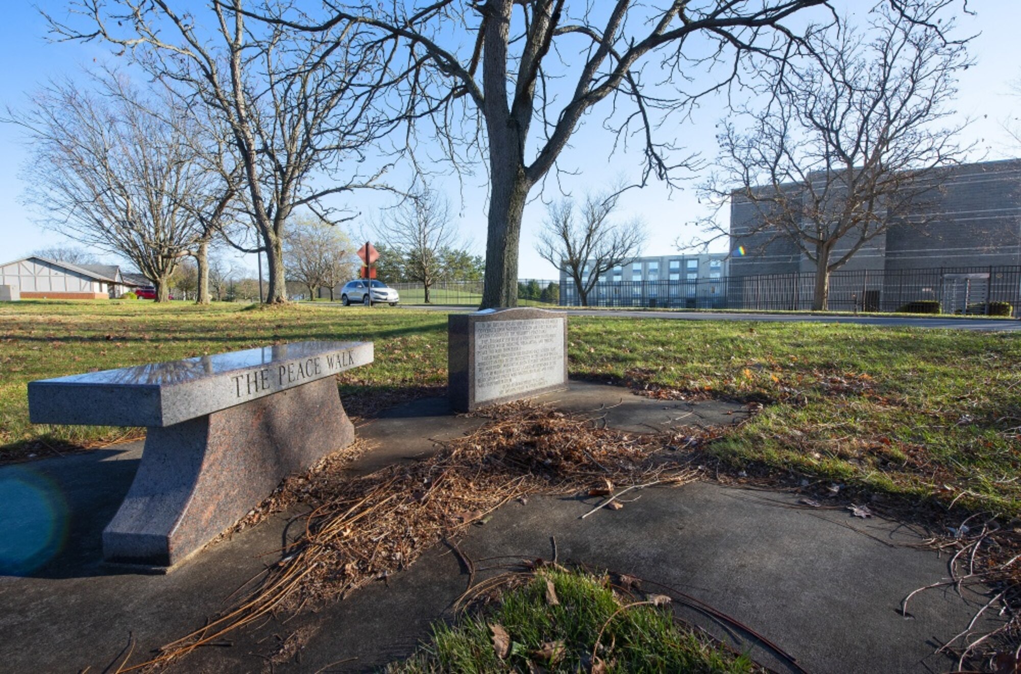 A bench and plaque commemorate the Peace Walk, a winding sidewalk between the Hope Hotel (background), which served as site of the official negotiations leading to the Dayton Peace Accords, and visiting officer quarters on Wright-Patterson Air Force Base, where the diplomats stayed. The unofficial talks that happened as the diplomats walked back and forth are credited with playing a role in the successful end of the Bosnian War. (U.S. Air Force photo by R.J. Oriez)