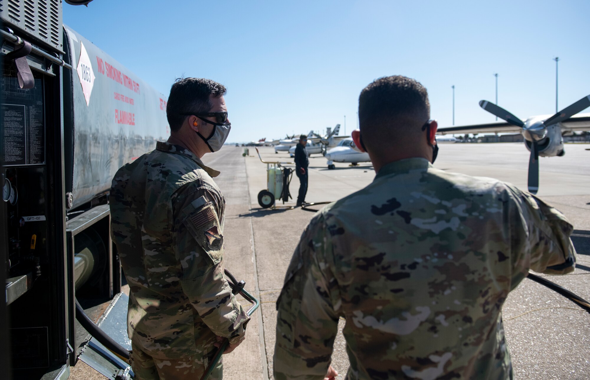 U.S. Air Force Airmen stand next to R-11 fuel truck during refueling of a MU-2 aircraft.
