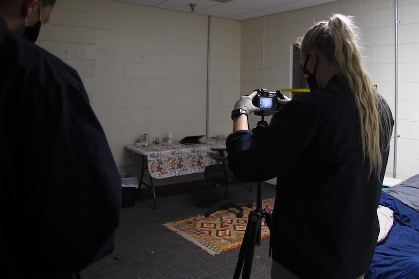 U.S. Air Force Special Agent Morgan Cebula, Detachment 331 Office of Special Investigations, documents the mock crime scene by taking photos in a staged dorm room at Joint Base Andrews, Md., Oct. 30, 2020. Photographs are taken at various angles and distances.