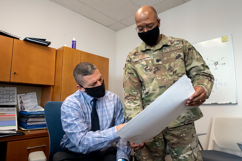 Two men review paperwork in an office.