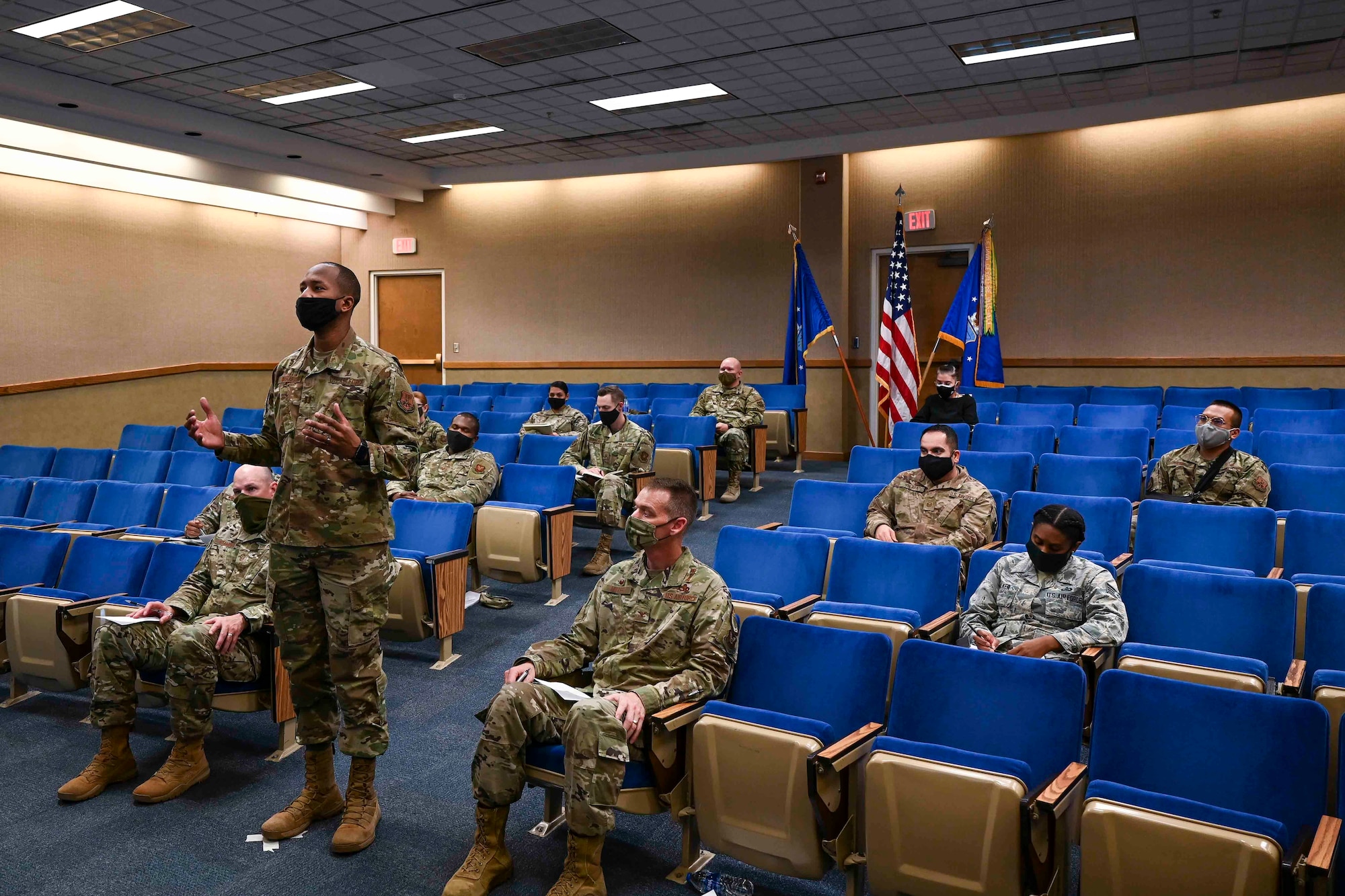 Airmen sitting in an auditorium listening to a speaker