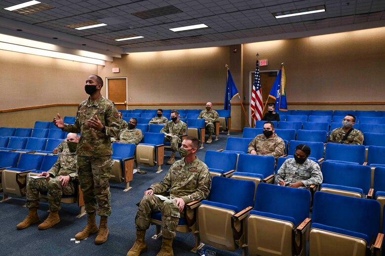 Airmen sitting in an auditorium listening to a speaker