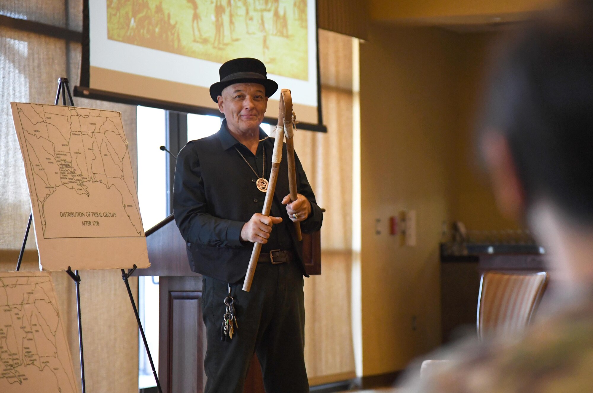 GrayHawk Perkins demonstrates how stick ball is played to Keesler personnel inside the Bay Breeze Event Center at Keesler Air Force Base, Mississippi, Nov. 19, 2020. Perkins visited Keesler to share his story about his life growing up as a Native American in celebration of Native American History Month. (U.S. Air Force photo by Kemberly Groue)