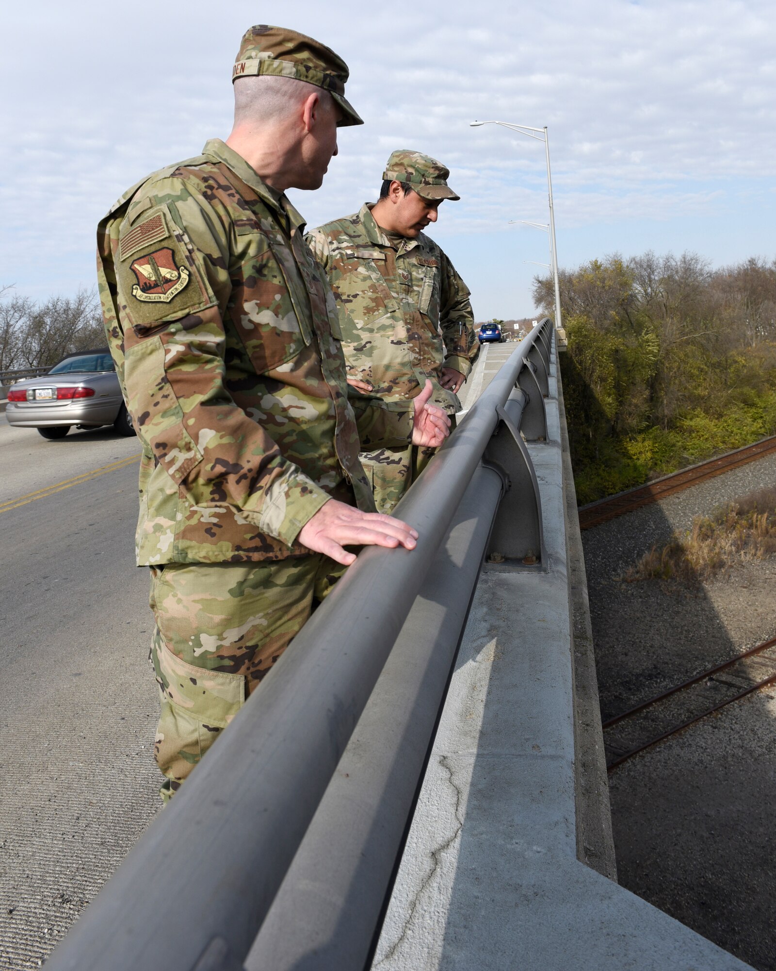 U.S. Air Force Senior Master Sgt. David Briden, left, Air Force Installation Contracting Center expeditionary operations manager, and Tech. Sgt. Anthony Staton, National Air and Space Intelligence Center, stand on the South Maple Avenue bridge in Fairborn, Ohio, on Nov. 20, 2020. Two days earlier, the Airmen assigned to Wright-Patterson Air Force Base stopped to aid a teen who was hanging over the side of the bridge and appeared to be in distress. They stayed with the teen until police and medics arrived. A portion of the photo has been altered for security reasons. (U.S. Air Force photo by Ty Greenlees)