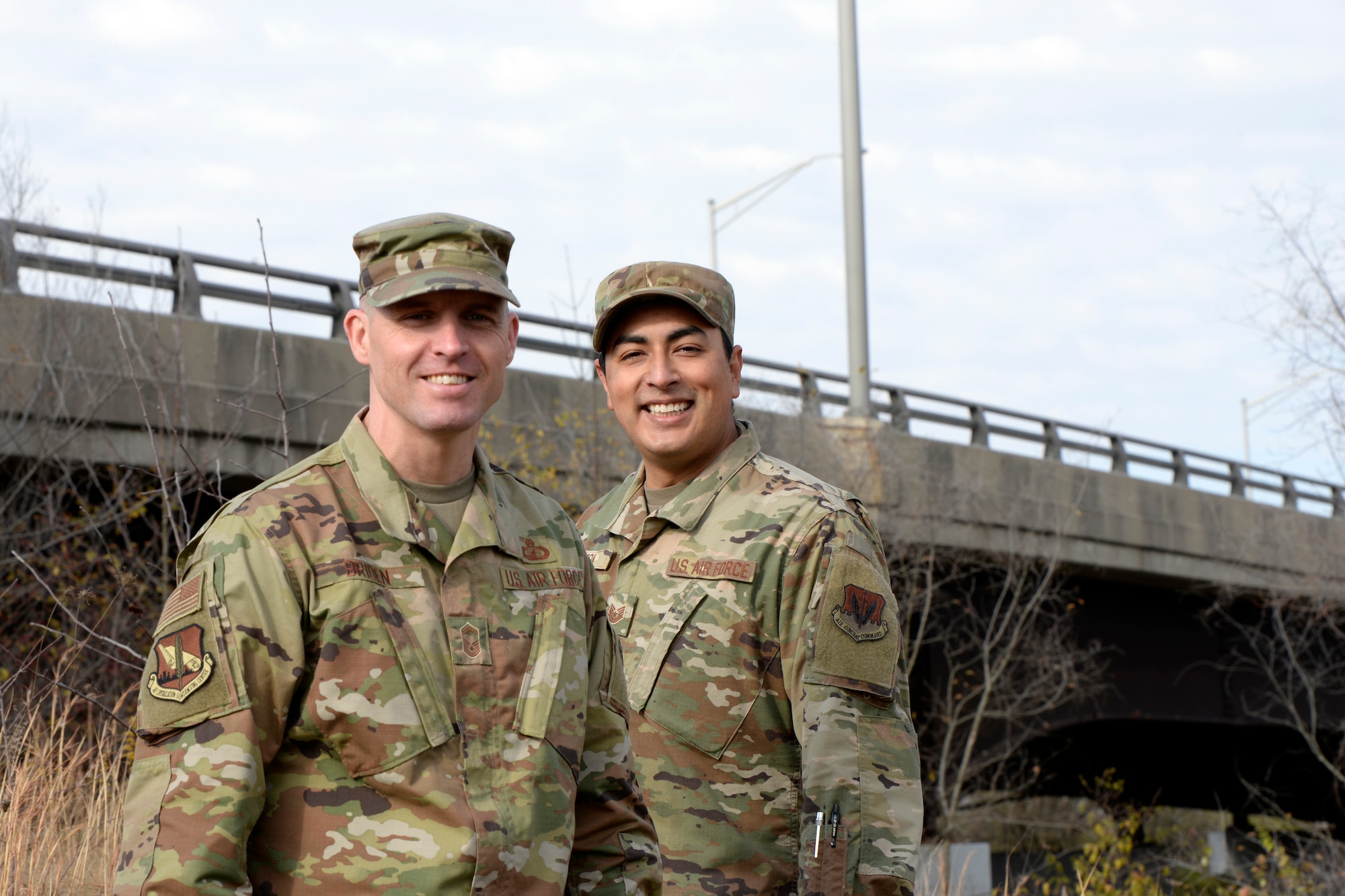 U.S. Air Force Senior Master Sgt. David Briden, left, Air Force Installation Contracting Center expeditionary operations manager, and Tech. Sgt. Anthony Staton, National Air and Space Intelligence Center, stand on the South Maple Avenue bridge in Fairborn, Ohio, on Nov. 20, 2020. Two days earlier, the Airmen assigned to Wright-Patterson Air Force Base stopped to aid a teen who was hanging over the side of the bridge and appeared to be in distress. They stayed with the teen until police and medics arrived. A portion of the photo has been altered for security reasons. (U.S. Air Force photo by Ty Greenlees)