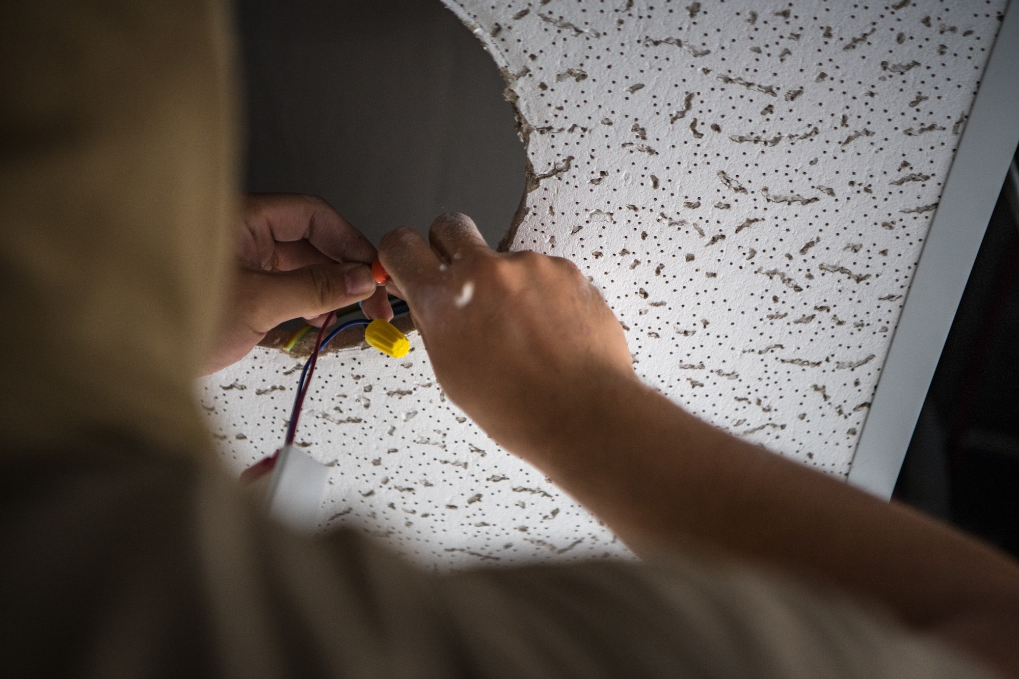 Senior Airman Andy Hoang, an electrical systems specialist with the 379th Expeditionary Civil Engineer Squadron facility management team, uses a twist-on end cap to splice two wires together as he connects a new LED lamp Oct. 27, 2020, at Al Udeid Air Base, Qatar. The 379th ECES facility management team has been tasked to address minor maintenance issues in every dorm building on base, improving the quality of life for service members stationed at AUAB. (U.S. Air National Guard photo by Tech. Sgt. Brigette Waltermire)