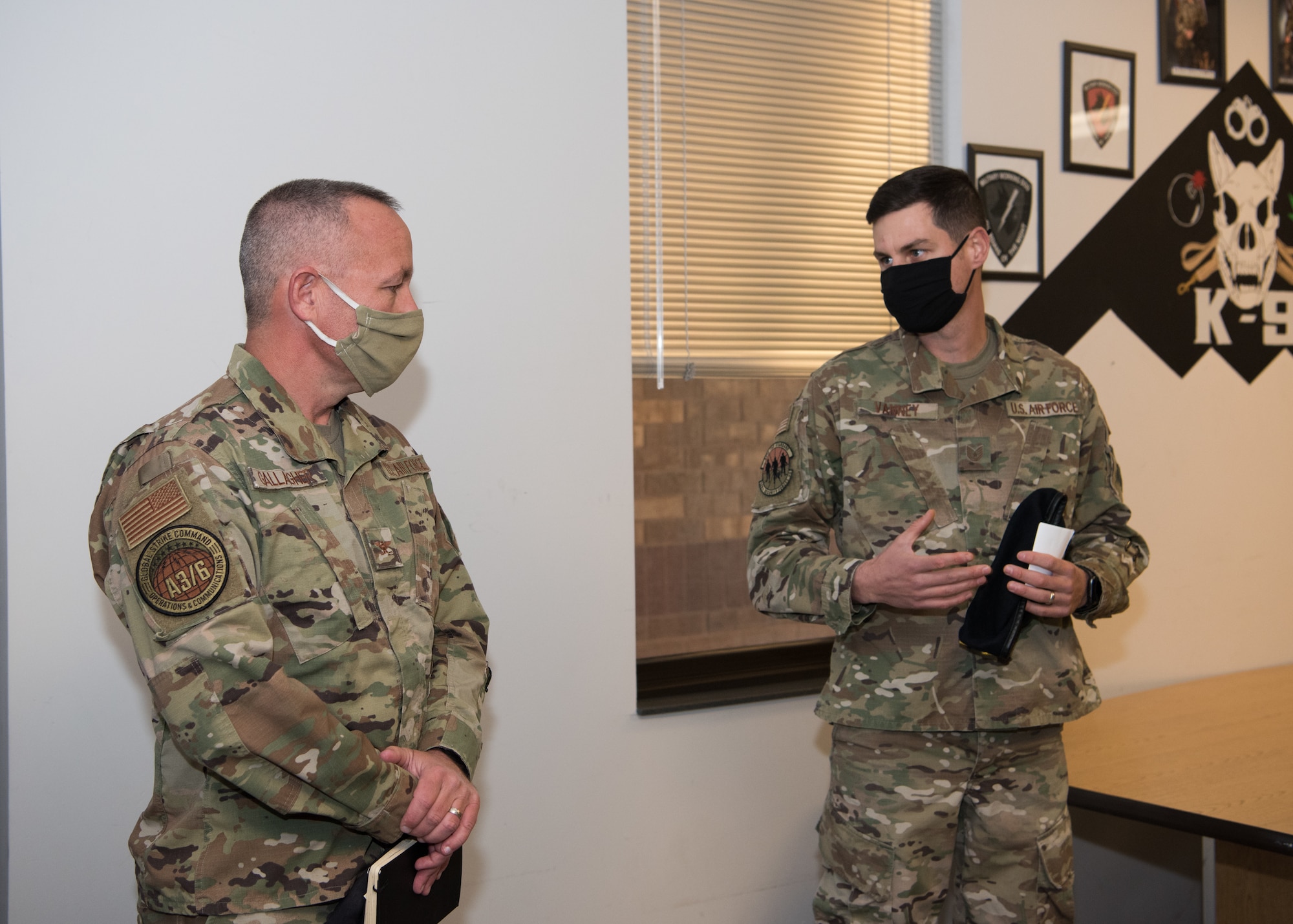 U.S. Air Force Col. Chad Gallagher, Air Force Global Strike Command chief of Security Forces, listens to U.S. Air Force Tech. Sgt. Benjamin Vanney, 509th Security Forces Squadron military working dog trainer, talk about the MWD program at the kennels.