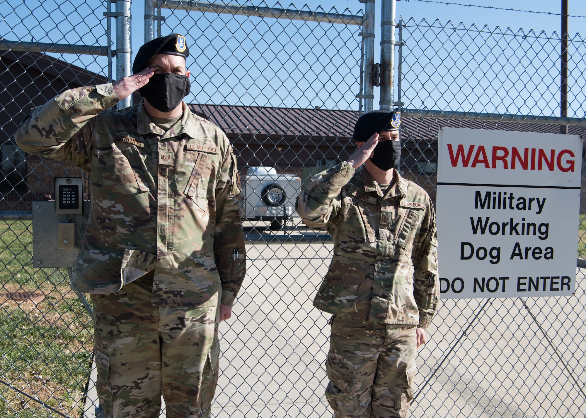 Two Airmen salute  U.S. Air Force Col. Chad Gallagher, Air Force Global Strike Command chief of Security Forces, outside the kennels.