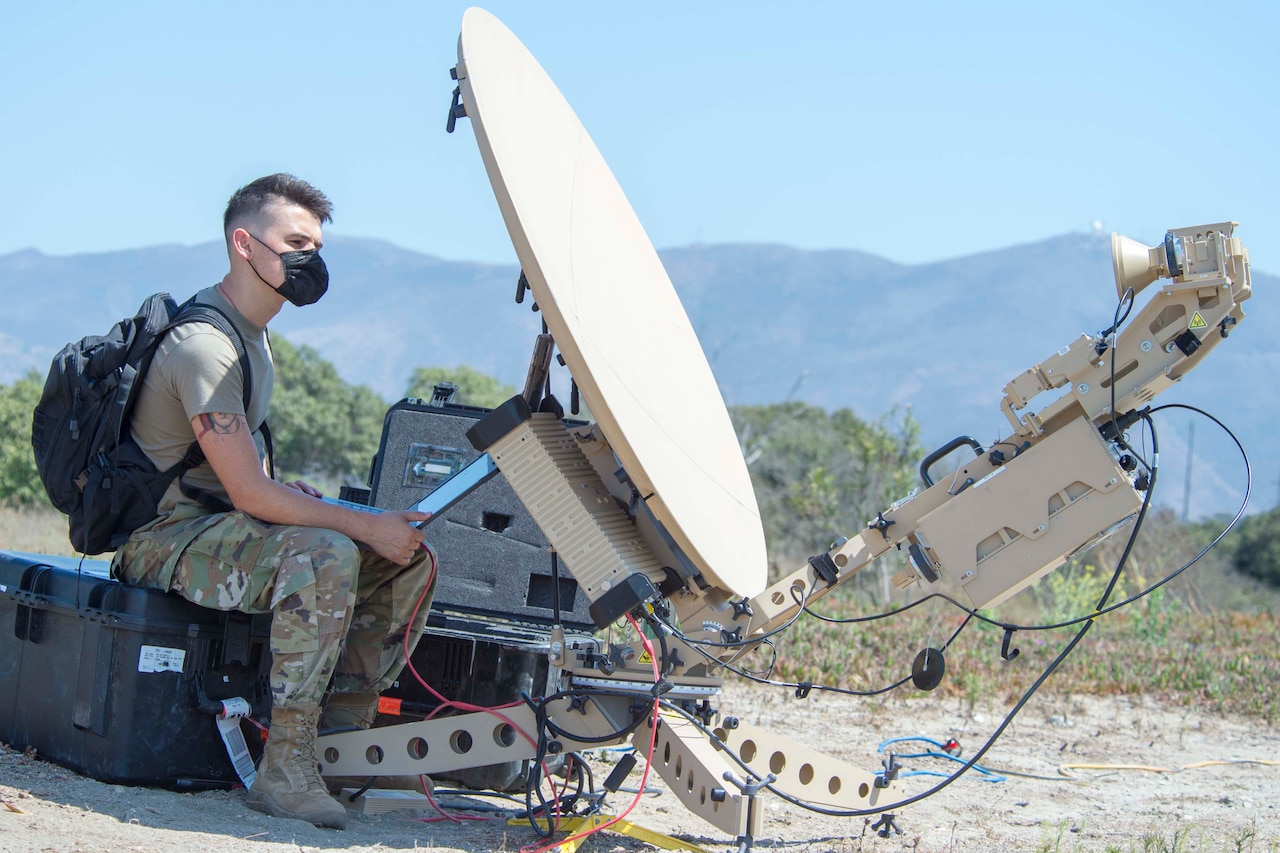 An airman sets up a satellite antenna.