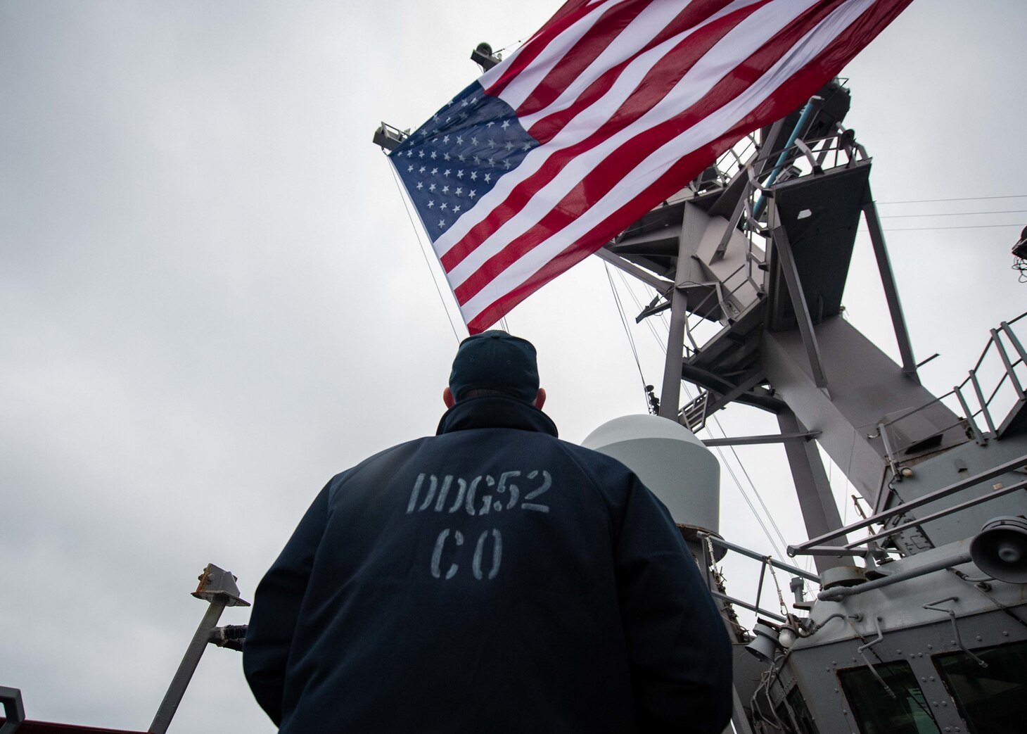 SOUTH CHINA SEA (Nov. 21, 2020) Cmdr. Chris Gahl, commanding officer of guided-missile destroyer USS Barry (DDG 52), watches as the battle ensign is raised during routine underway operations. Barry is forward-deployed to the U.S. 7th Fleet area of operations in support of a free and open Indo-Pacific. (U.S. Navy photo by Mass Communication Specialist Molly Crawford)