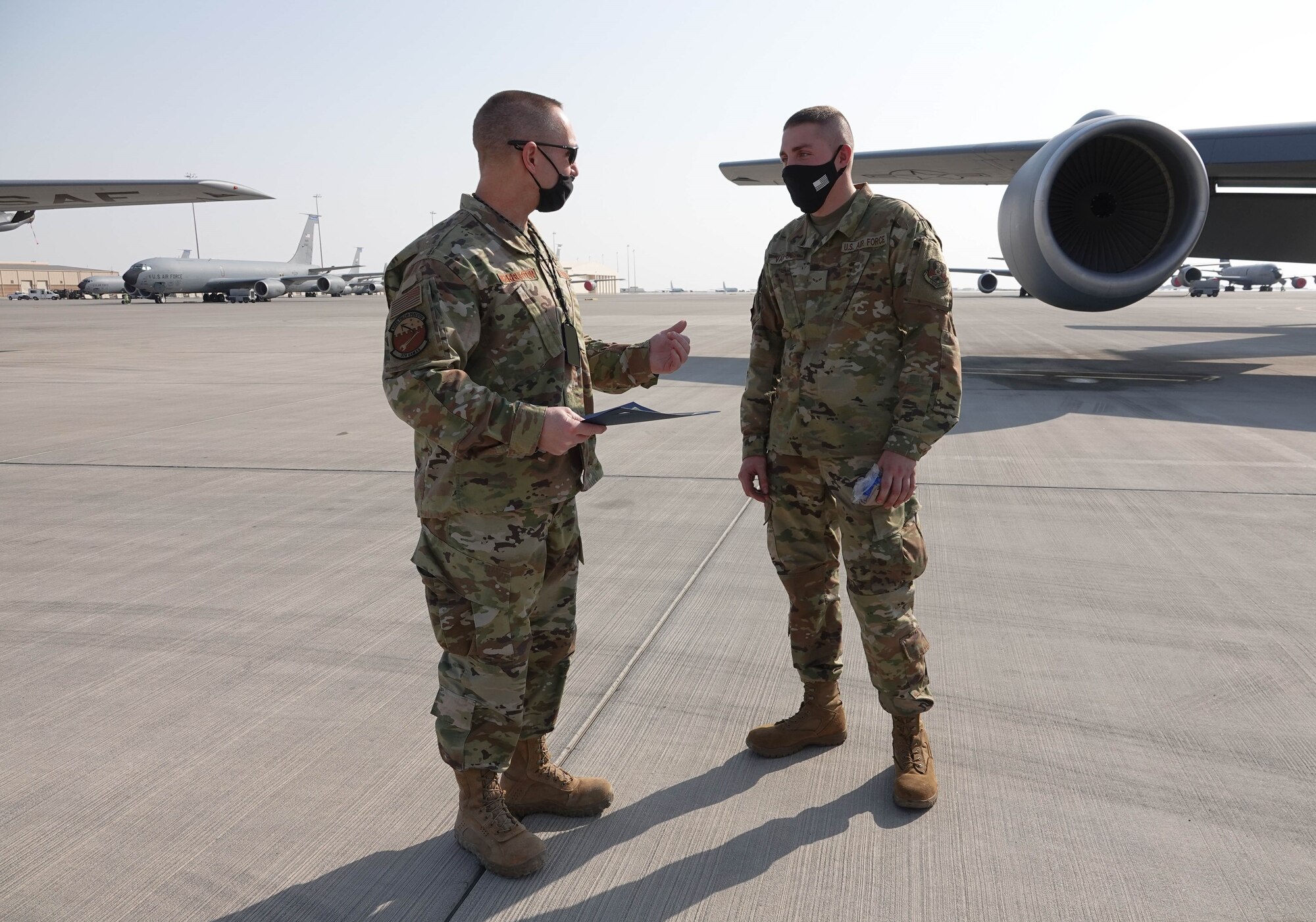 U.S. Air Force Lt. Col. Dennis Warburton, acting 379th Expeditionary Aircraft Maintenance Squadron commander, talks to U.S. Air Force Airman 1st Class Trever Van Oss, with the 379th Expeditionary Logistics Readiness Squadron, during his crew chief for a day experience Nov. 17, 2020, at Al Udeid Air Base, Qatar. Van Oss helped launch a KC-135 Stratotanker aircraft alongside maintenance Airmen, marshalled it into a parking spot and serviced the engine oil after the aircraft shut down. The crew chief for a day program provides interested Airmen of any military specialty, direct exposure to the 379th Air Expeditionary Wing's robust aerial refueling capability. (Photo courtesy of the U.S. Air Force) (ID badge obscured for OPSEC)