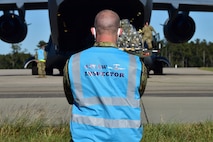U.S. Air Force Tech. Sgt. Andrew Chilcoat, a 437th Airlift Wing Air Traffic Safety Electronics Personnel (ATSEP) evaluator, monitors as Airmen offload cargo from a C-17 Globemaster III at McEntire Joint National Guard Base, S.C., Nov. 16, 2020. Palmetto Challenge is a global mobilization exercise held at McEntire Joint National Guard Base, S.C. The exercise is held in order to develop readiness and awareness in a simulated deployed environment for over 100 Airmen from Joint Base Charleston.