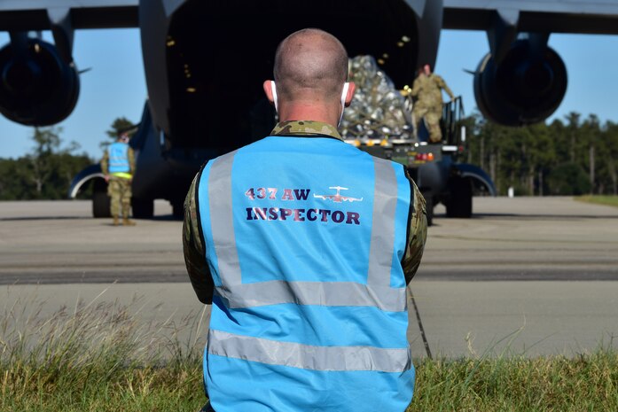 U.S. Air Force Tech. Sgt. Andrew Chilcoat, a 437th Airlift Wing Air Traffic Safety Electronics Personnel (ATSEP) evaluator, monitors as Airmen offload cargo from a C-17 Globemaster III at McEntire Joint National Guard Base, S.C., Nov. 16, 2020. Palmetto Challenge is a global mobilization exercise held at McEntire Joint National Guard Base, S.C. The exercise is held in order to develop readiness and awareness in a simulated deployed environment for over 100 Airmen from Joint Base Charleston.