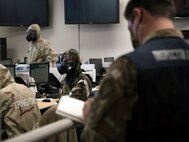 U.S. Air Force Master Sgt. Ian Ouellette, the superintendent for the 628th Air Base Wing Inspector General office, grades Airmen from the Emergency Operations Center (EOC) on how efficiently they equip Mission Oriented Protective Posture gear (MOPP), at McEntire Joint National Guard Base, S.C., Nov. 16, 2020. Palmetto Challenge is a global mobilization exercise held at McEntire Joint National Guard Base, S.C. The exercise is held in order to develop readiness and awareness in a simulated deployed environment for over 100 Airmen from Joint Base Charleston.