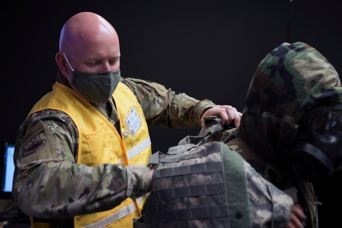 U.S. Air Force Capt. Alexander Arntz, a 315th Operations Support Squadron Intelligence Wing Inspection Team member, helps an Airmen from the Crisis Action Team (CAT) don Mission Oriented Protective Posture gear (MOPP) at McEntire Joint National Guard Base, S.C., Nov. 16, 2020. Palmetto Challenge is a global mobilization exercise held at McEntire Joint National Guard Base, S.C., and Pope Army Airfield, N.C. The exercise is held in order to develop readiness and awareness in a simulated deployed environment for over 100 Airmen from Joint Base Charleston.