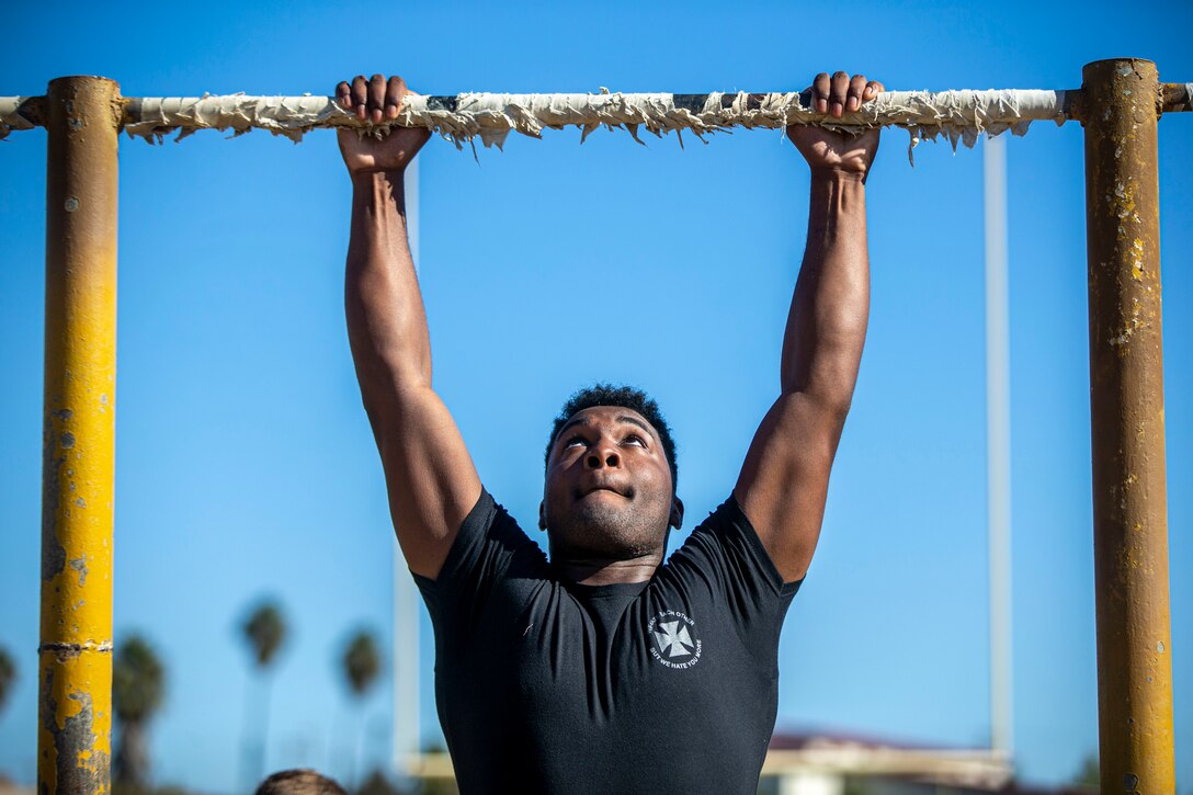 A man pulls himself up to a bar.