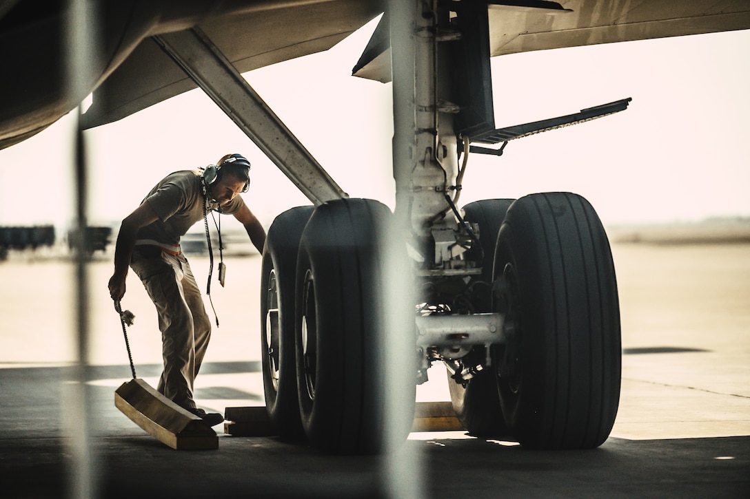 An airman removes chalks from around the large tires of an aircraft.