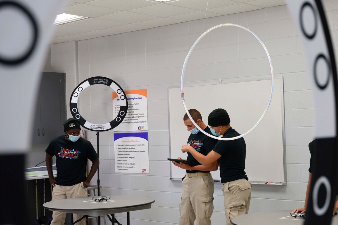 Students look over an iPad as they plot coordinates for a drone.