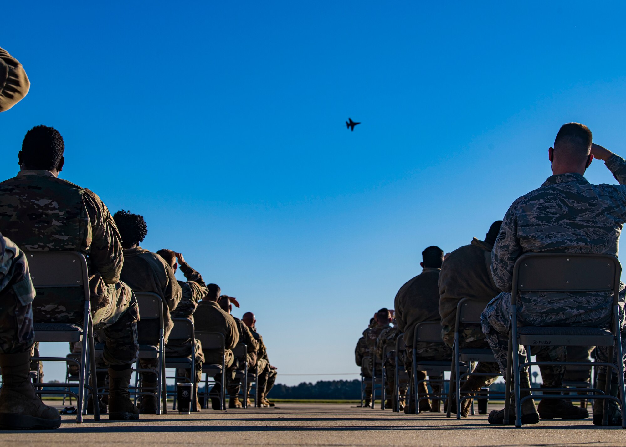 A photo of a group of Airmen watch a demonstration on the flightline.
