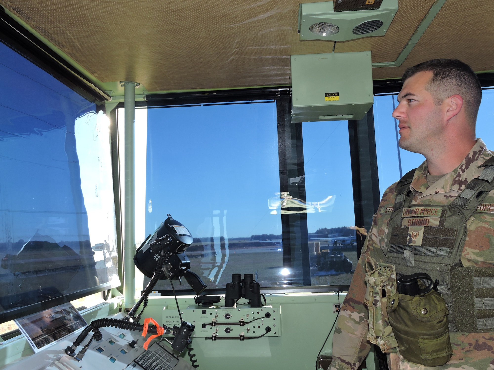 Photo of an Airman looking out the windows from inside a control tower.
