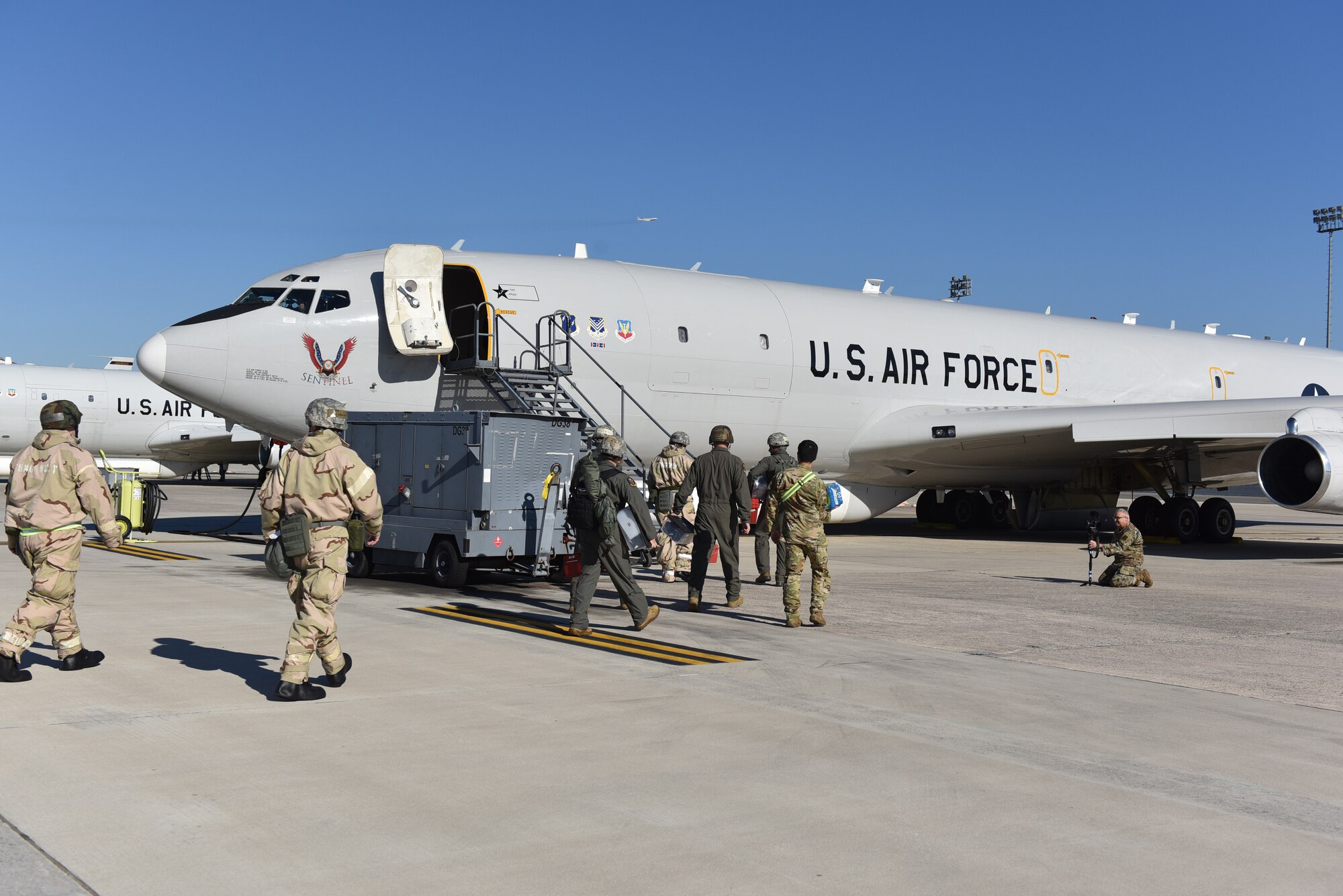 Photo shows Airmen walking up stairs into an aircraft.