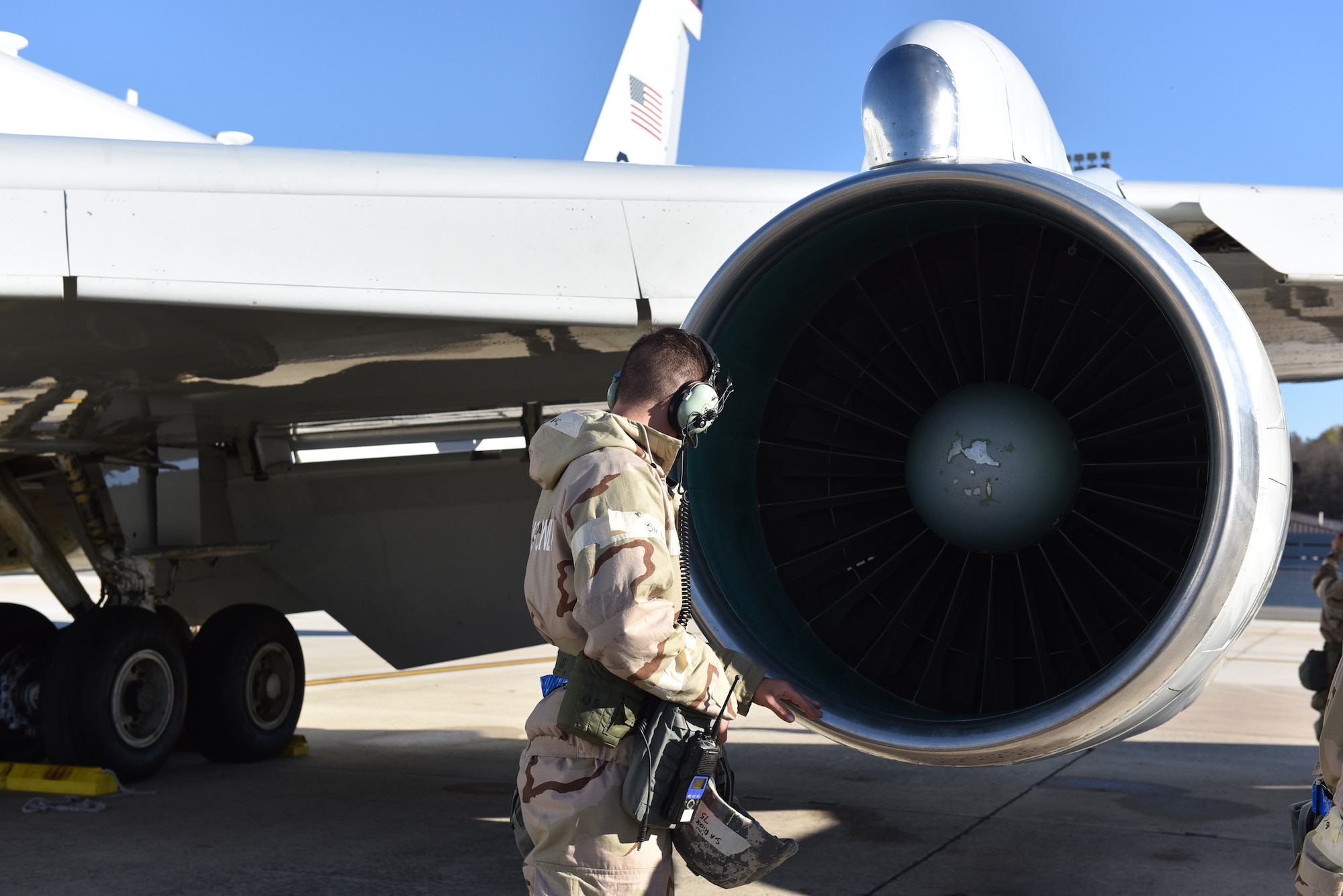 Photo shows an Airman looking into the intake of an aircraft.