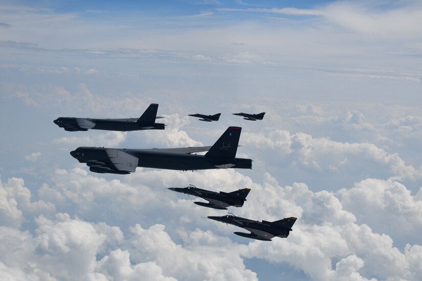 U.S. aircraft and Colombian aircraft fly in formation over clouds.