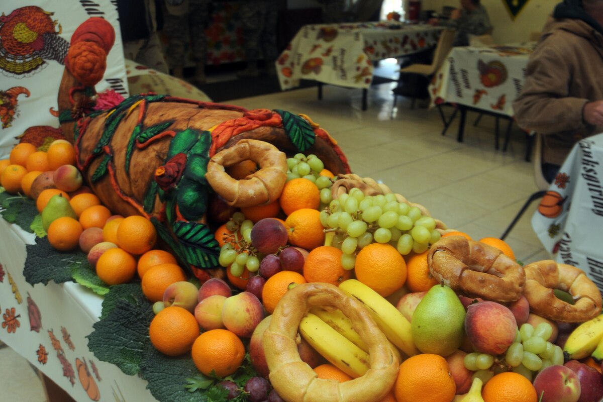 A cornucopia of fruit and bread is on a table.