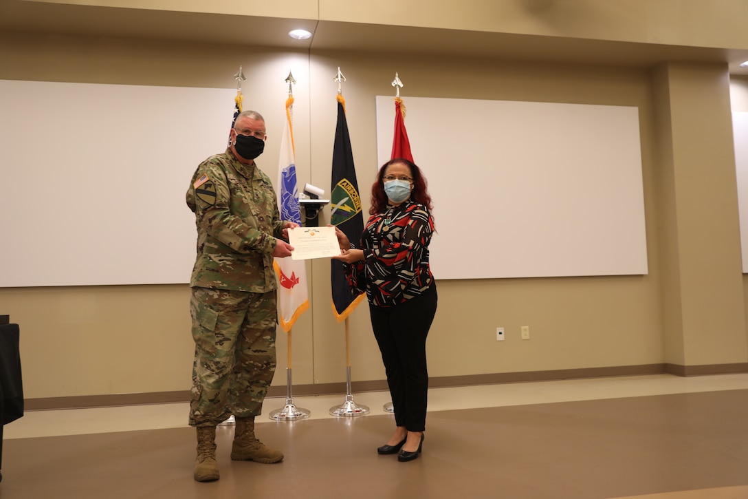U.S. Army Civil Affairs and Psychological Operations Command (Airborne) Commanding General, Brig. Gen. Jeffrey C. Coggin, presents the Commanders Award for Civilian Service to Elizabeth Fernandez-Javier during the Soldier and Department of the Army Civilian recognition award ceremony at USACAPOC(A) Headquarters, Fort Bragg, N.C., Nov. 17, 2020. The recognition award ceremony was held to recognize 12 USACAPOC(A) Soldiers and DA civilians for Federal Length of Service Awards, Honorary Awards, Retirement recognition, and military awards.