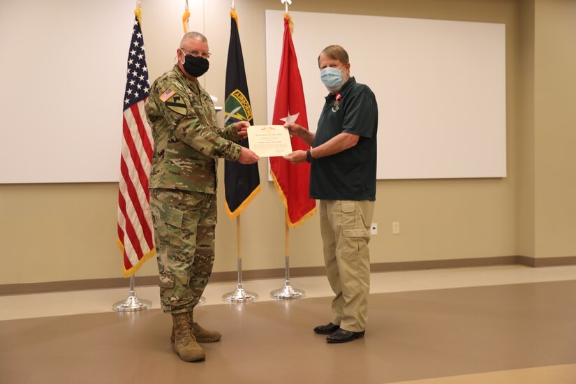 U.S. Army Civil Affairs and Psychological Operations Command (Airborne) Commanding General, Brig. Gen. Jeffrey C. Coggin, presents the Superior Civilian Service Award to Robert E. Spears for service as the Training Specialist for USACAPOC(A) for over 28 years, and recognizes his impending retirement from federal service, presenting a Department of the Army Certificate of Appreciation, during the Soldier and Department of the Army Civilian recognition award ceremony at USACAPOC(A) Headquarters, Fort Bragg, N.C., Nov. 17, 2020. The recognition award ceremony was held to recognize 12 USACAPOC(A) Soldiers and DA civilians for Federal Length of Service Awards, Honorary Awards, Retirement recognition, and military awards.