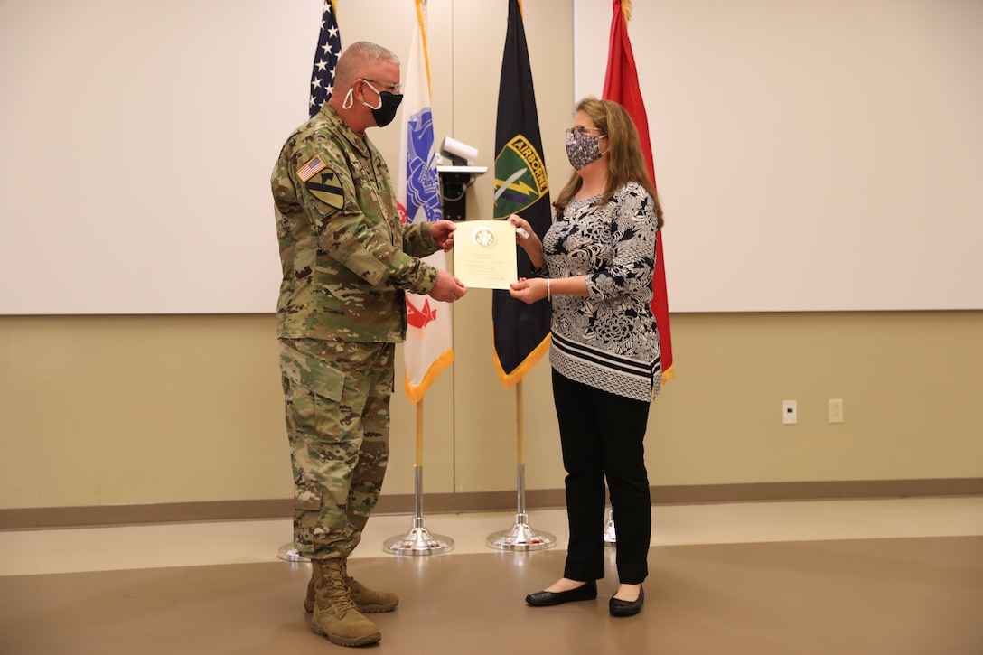 U.S. Army Civil Affairs and Psychological Operations Command (Airborne) Commanding General, Brig. Gen. Jeffrey C. Coggin, presents the Federal Length of Service Award to Elizabeth J. Holman for 40 years of federal service, and recognizes her impending retirement from federal service, presenting a Department of the Army Certificate of Appreciation, during the Soldier and Department of the Army Civilian recognition award ceremony at USACAPOC(A) Headquarters, Fort Bragg, N.C., Nov. 17, 2020. The recognition award ceremony was held to recognize 12 USACAPOC(A) Soldiers and DA civilians for Federal Length of Service Awards, Honorary Awards, Retirement recognition, and military awards.