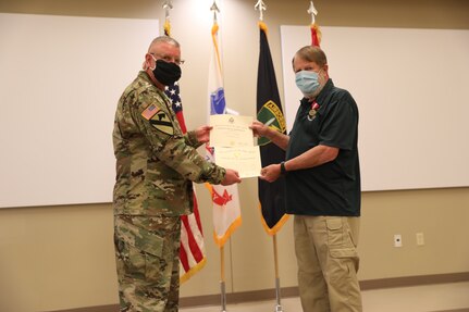 U.S. Army Civil Affairs and Psychological Operations Command (Airborne) Commanding General, Brig. Gen. Jeffrey C. Coggin, presents the Superior Civilian Service Award to Robert E. Spears for service as the Training Specialist for USACAPOC(A) for over 28 years, and recognizes his impending retirement from federal service, presenting a Department of the Army Certificate of Appreciation, during the Soldier and Department of the Army Civilian recognition award ceremony at USACAPOC(A) Headquarters, Fort Bragg, N.C., Nov. 17, 2020. The recognition award ceremony was held to recognize 12 USACAPOC(A) Soldiers and DA civilians for Federal Length of Service Awards, Honorary Awards, Retirement recognition, and military awards.
