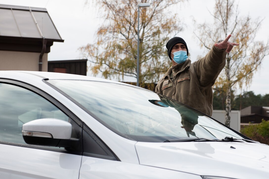 An Airman directs a car to the appropriate area in the drive-thru.