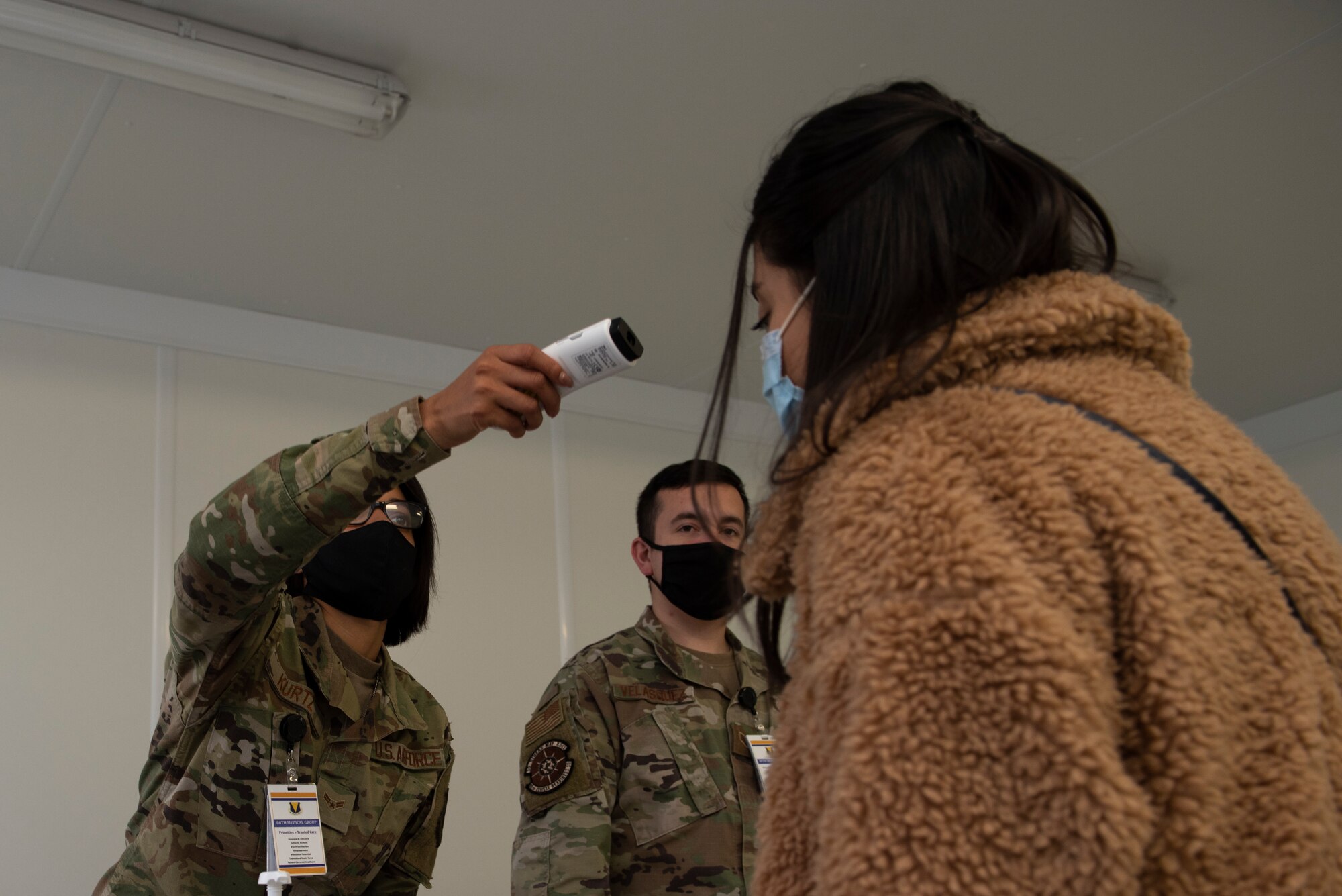 A photo of an Airman taking someone's temperature.