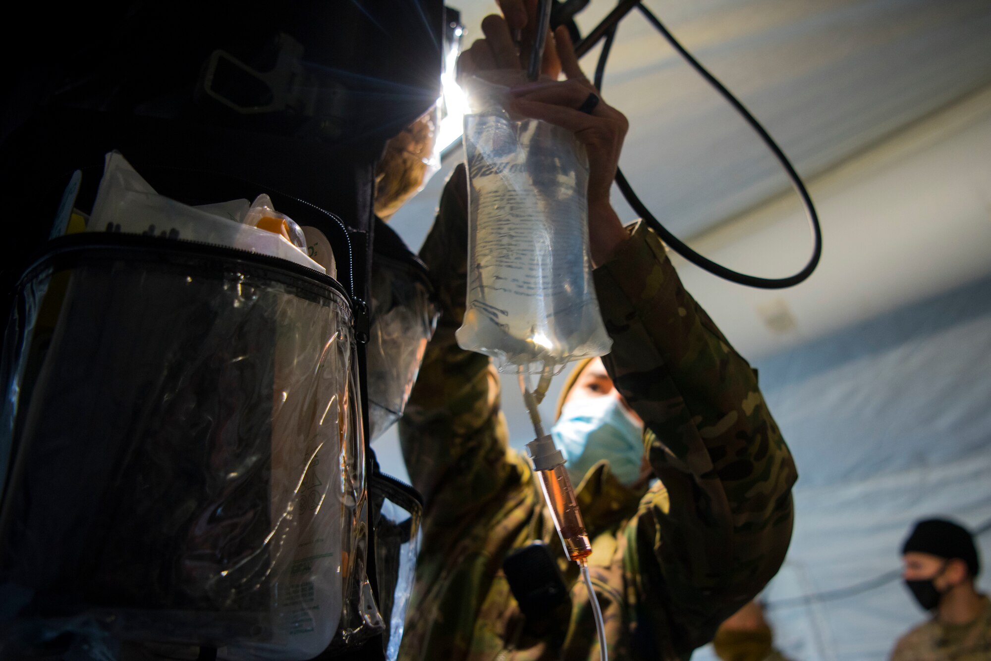 A U.S. Airman assigned to the 435th Contingency Response Support Squadron places an intravenous therapy fluid bag above a patient while participating in combat lifesaver training during exercise Agile Wolf 21-01.