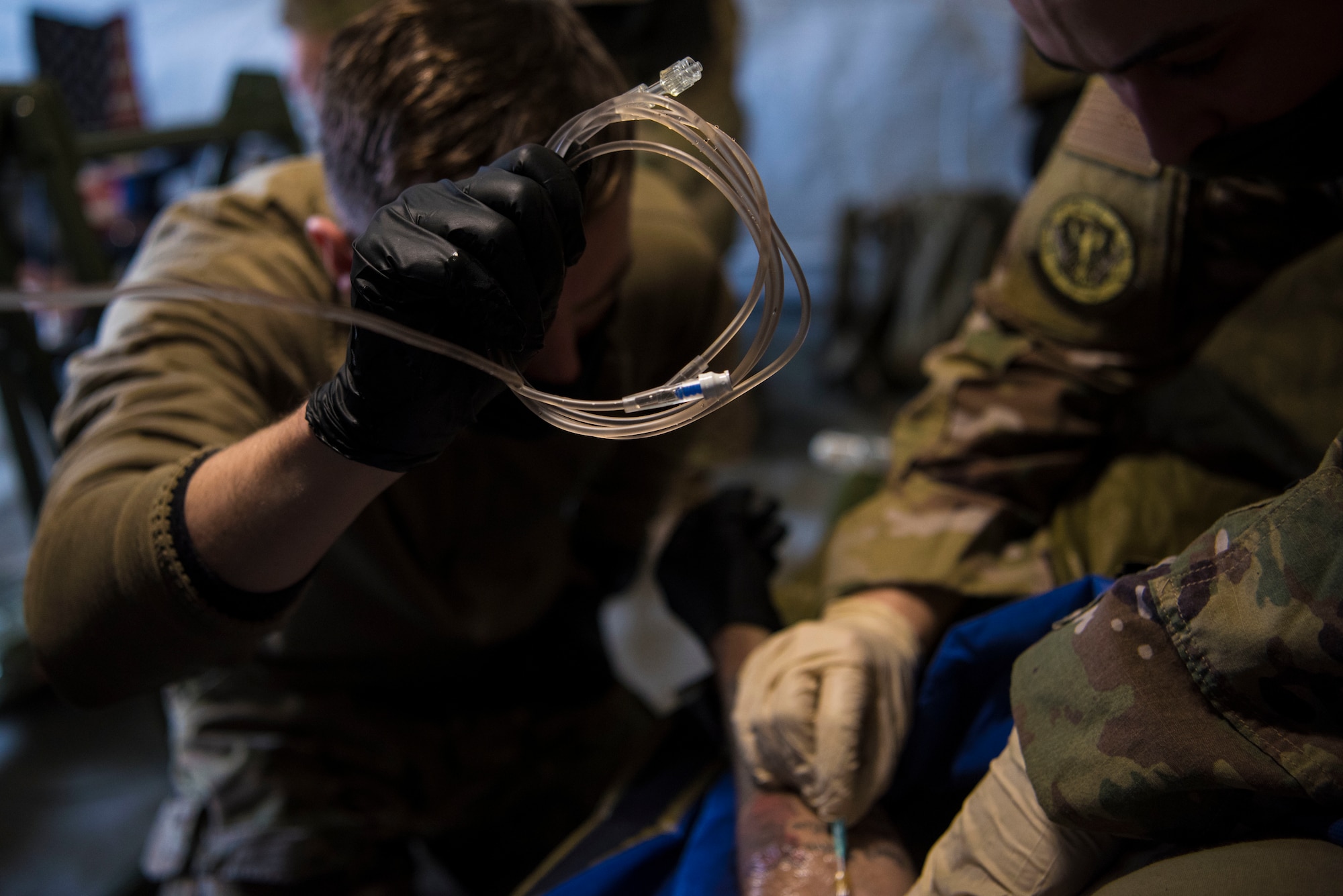 U.S. Air Force Staff Sgt. Lance Munsee, 435th Security Forces Squadron Phoenix First team member, left, watches Staff Sgt. Samuel Mow, 435th Contingency Response Support Squadron independent duty medical technician, demonstrate how to apply intravenous therapy during exercise Agile Wolf 21-01.
